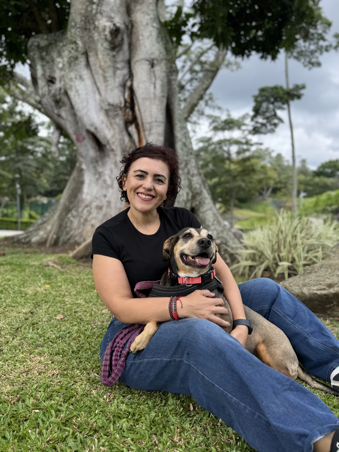Tania Hernández sentada en el pasto abrazando a su perro