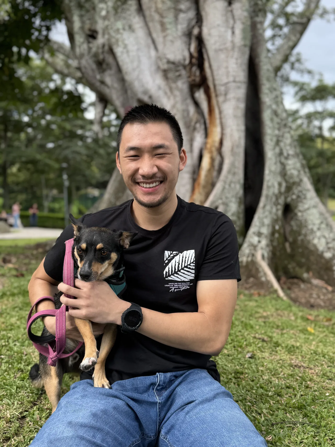 Wilson Gong Wu sentado en el pasto con su perro